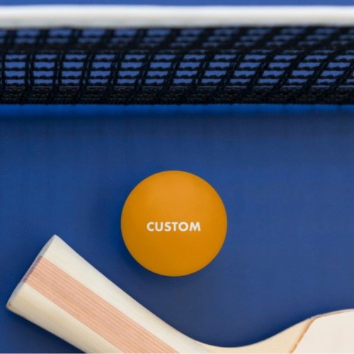 Personalized custom GLOW IN THE DARK YELLOW Table Tennis Ping Pong Ball pictured with bat in front of net.